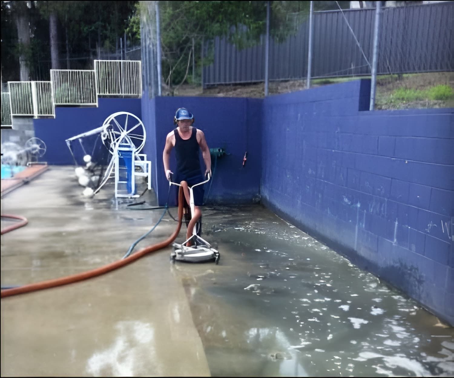 A Man Is Cleaning A Pool With A Machine — EcoPro Pressure Cleaning In Yatala, QLD