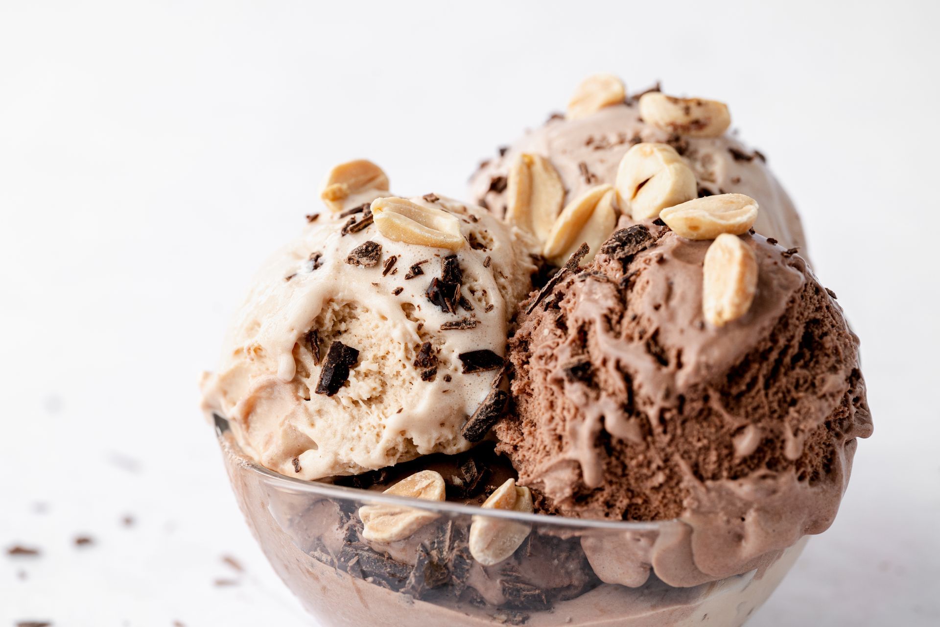Dve kepici sladoleda v stekleni skledi z arašidi na vrhu.