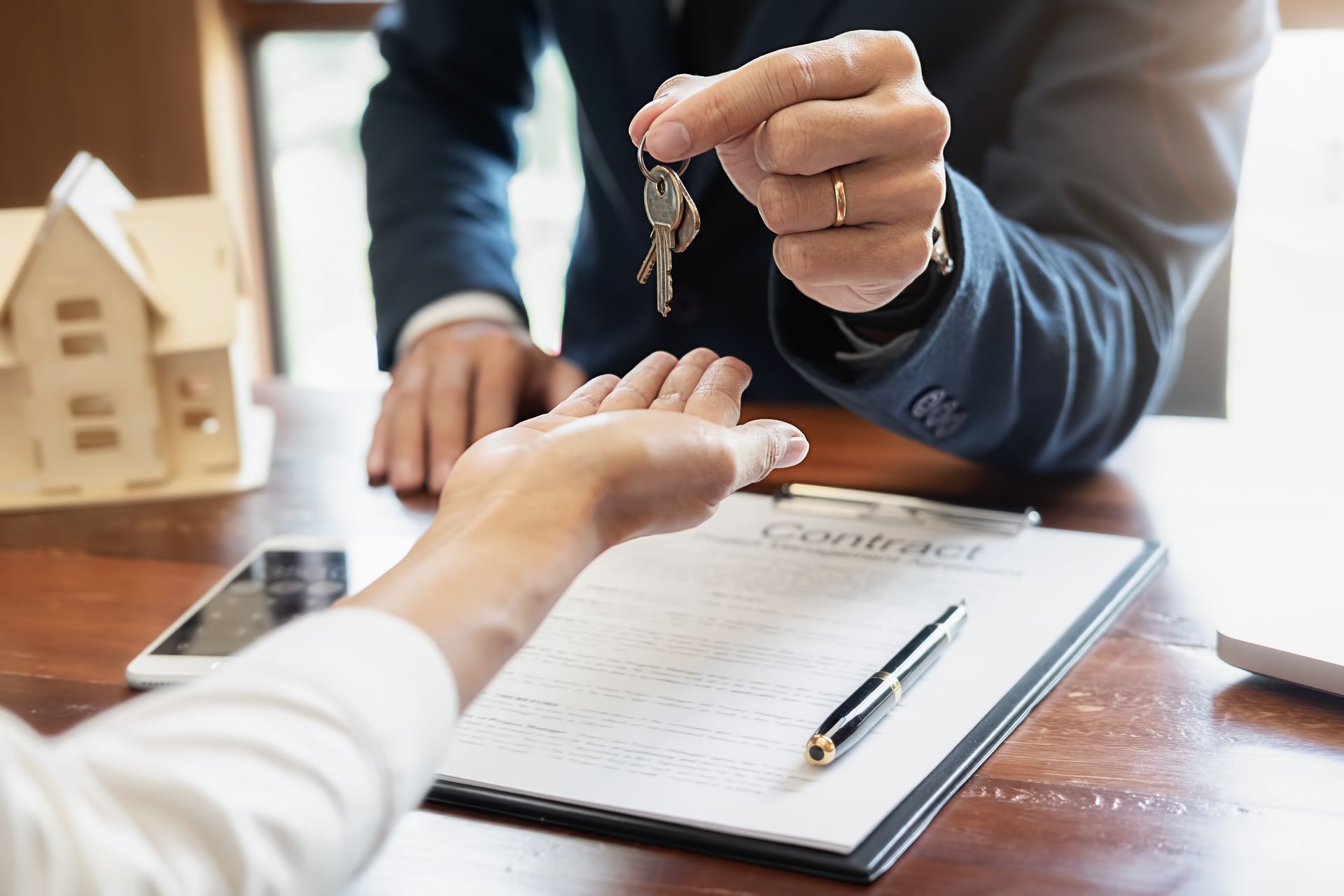 Person handing over a key during a real estate signing at a desk
