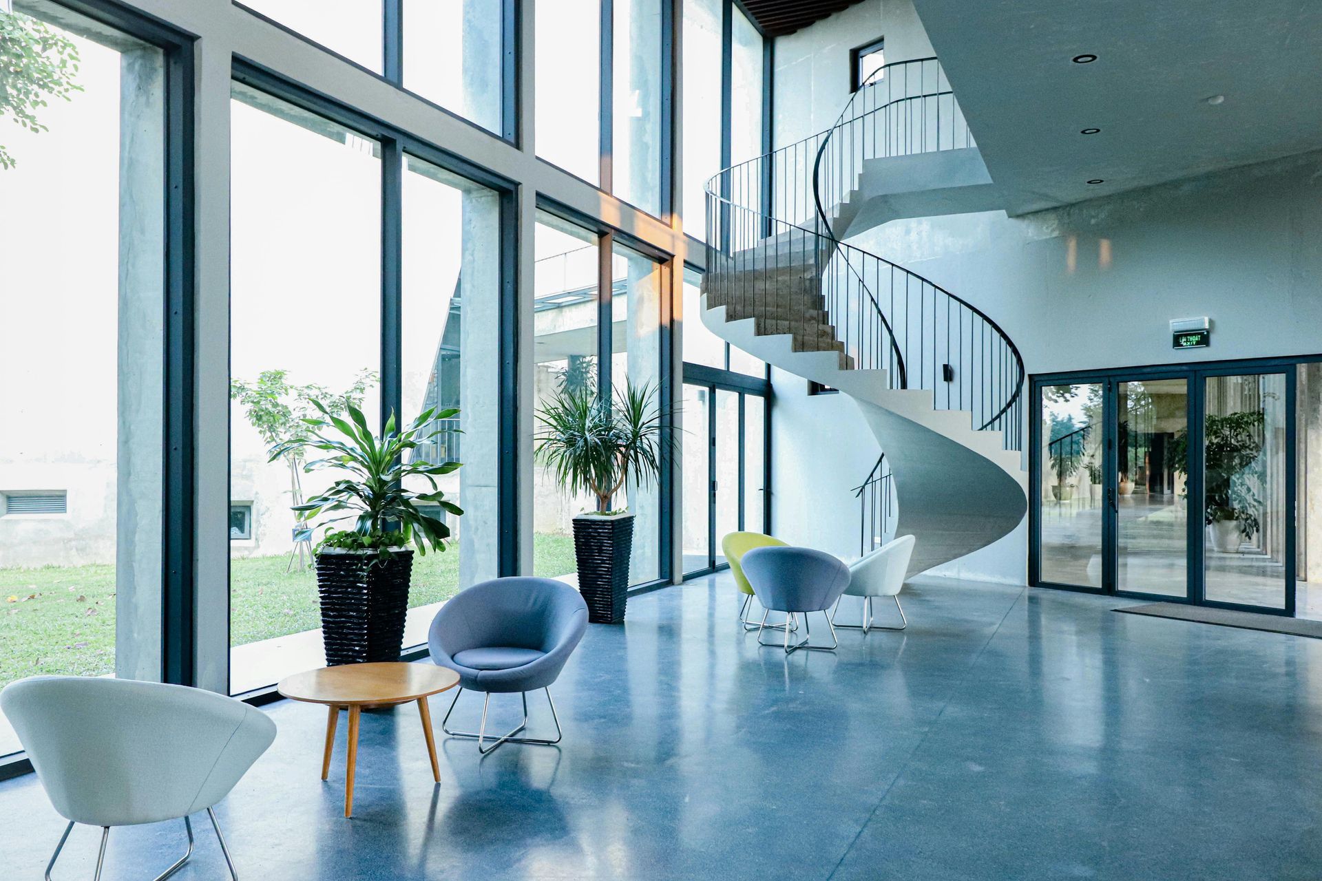 Modern lobby with gray stone pillars, wood-paneled walls, recessed linear ceiling lights, and a horizontal wall mirror.