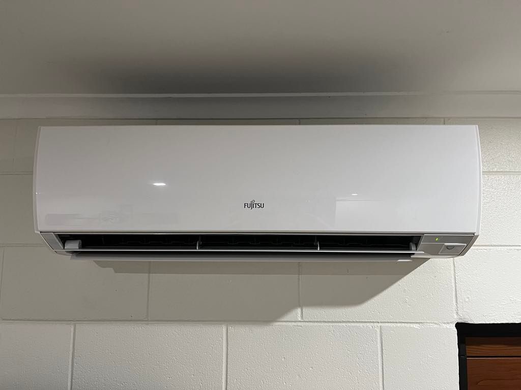 A white air conditioner is hanging from the ceiling in a room.