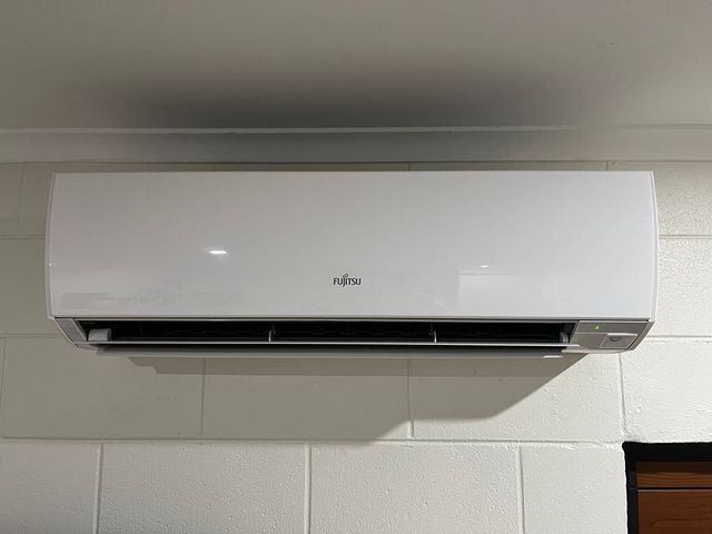 A white air conditioner is hanging from the wall in a room.