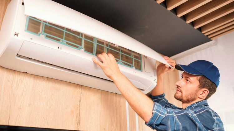 A man is cleaning the filter of an air conditioner.