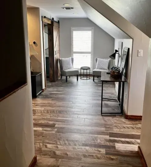 A living room with hardwood floors and a sliding barn door.