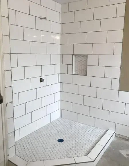 A bathroom with white tiles and a walk in shower.