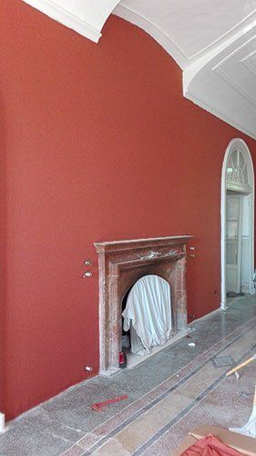 una sala con un camino e un muro dipinto di color rosso