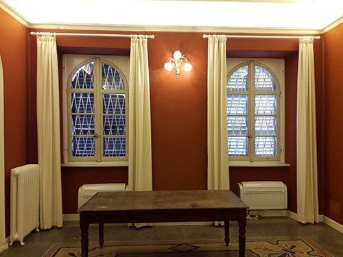 una stanza con due finestre e un tavolino in legno