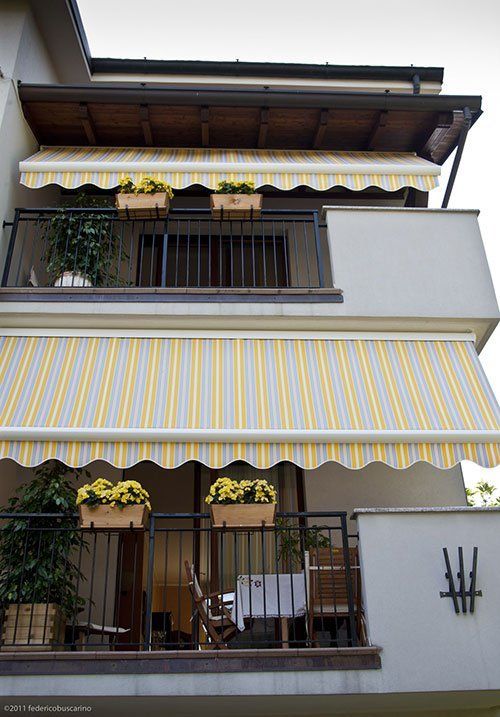 due balconi con delle tende da sole di color giallo e grigio