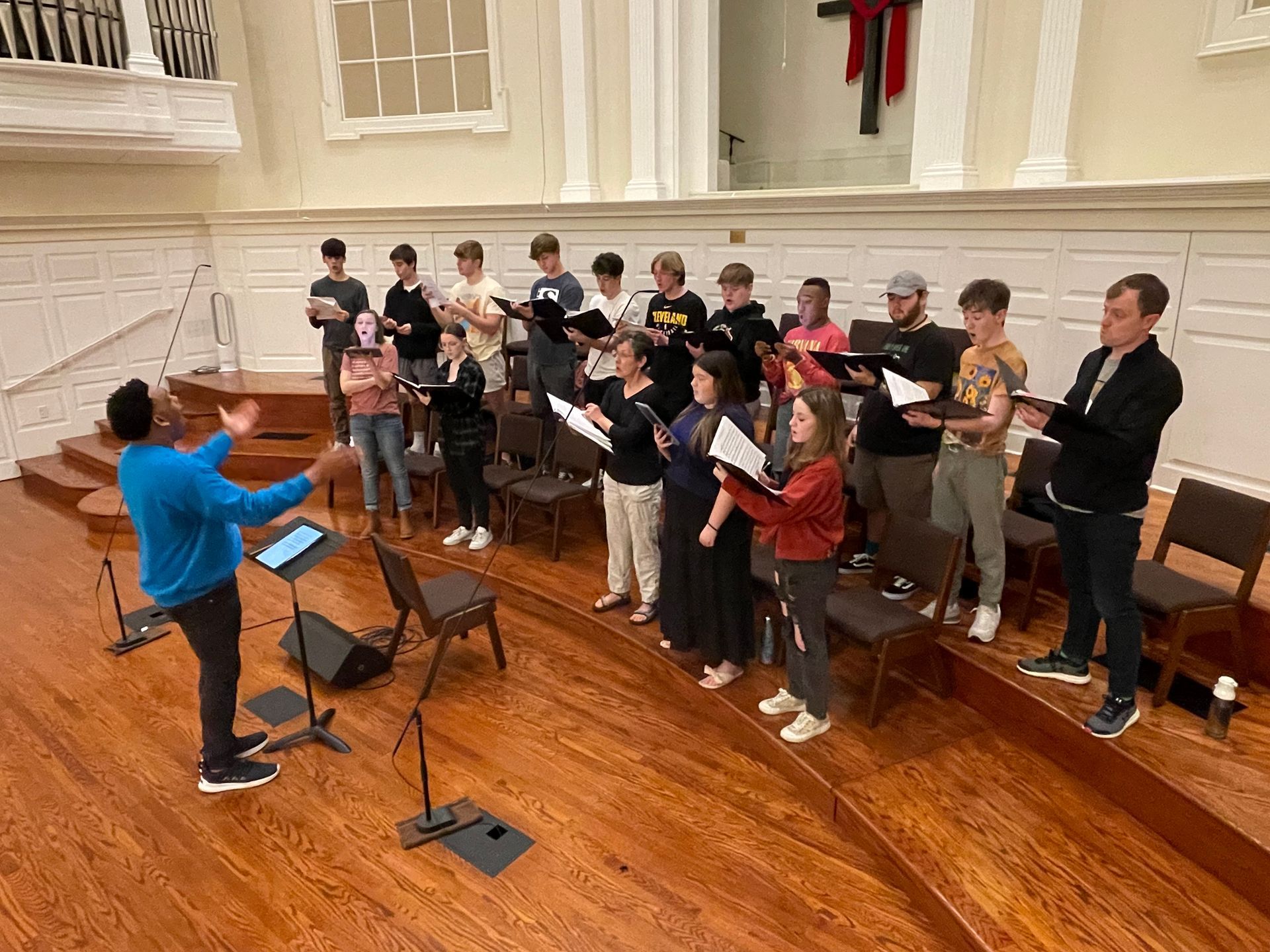 A man is leading a choir in a church.