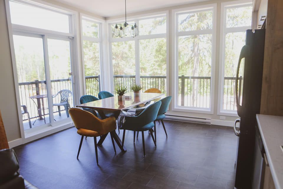 Une salle à manger avec une table et des chaises et beaucoup de fenêtres.