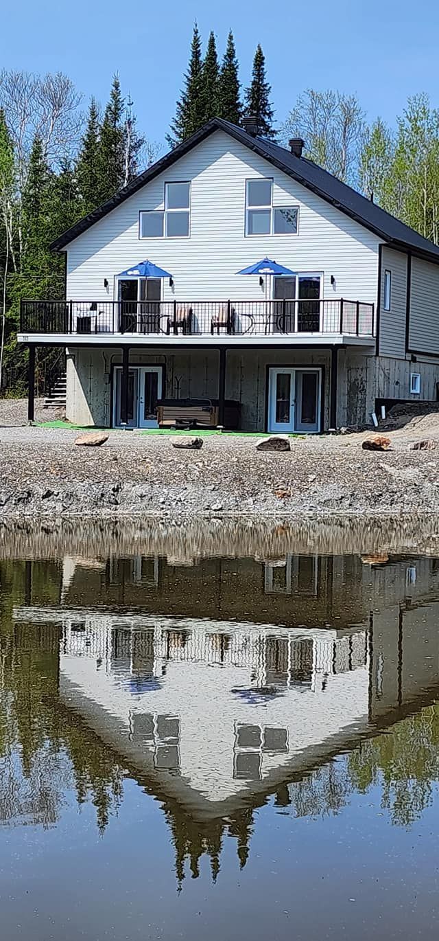 Une grande maison blanche se reflète dans un plan d'eau.