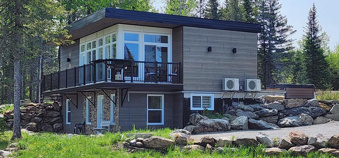 Une petite maison avec une grande terrasse se trouve au milieu d'un champ verdoyant.
