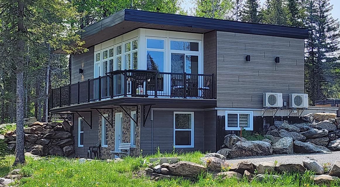 A small house with a balcony in the middle of a forest.