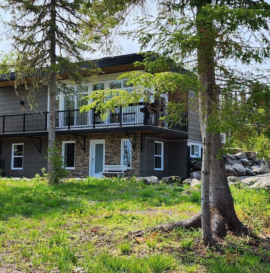 A large house with a balcony is surrounded by trees and grass.