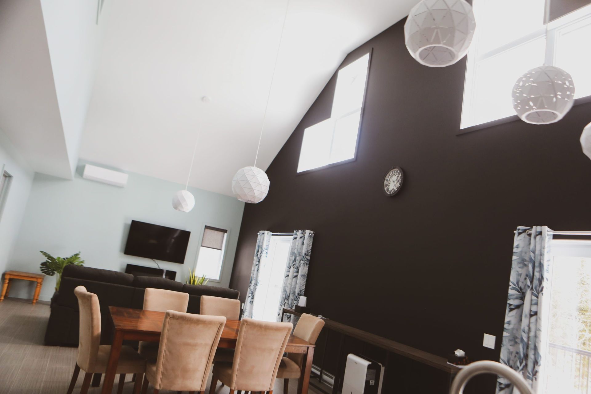 Un salon avec une table et des chaises et une horloge au mur