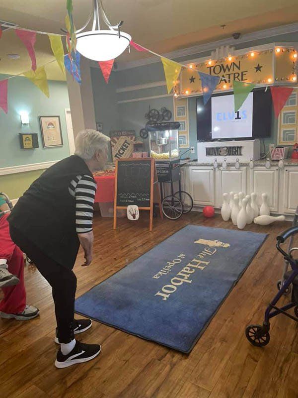 An elderly woman is playing bowling in a living room.