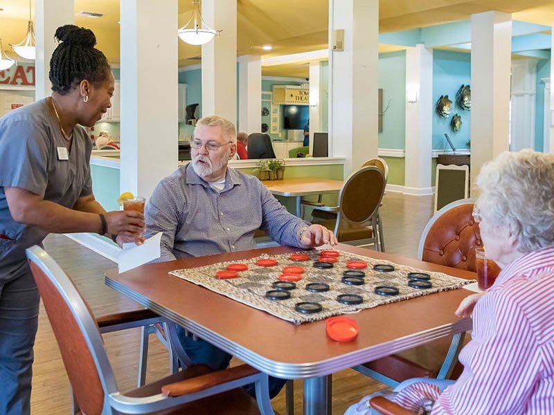 A group of elderly people are playing a game of checkers at a table.