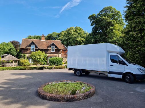 A moving truck with the back door open is parked in front of a brick house.