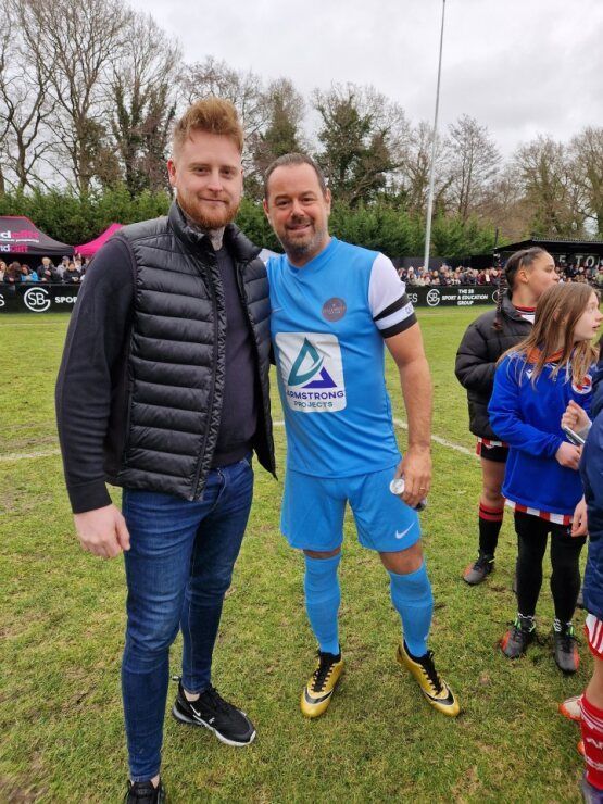 Two men are posing for a picture on a soccer field.