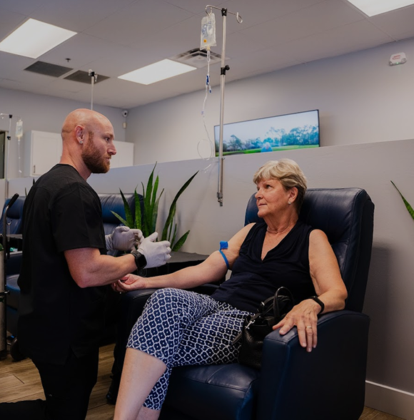 A man is kneeling down next to a woman in a chair