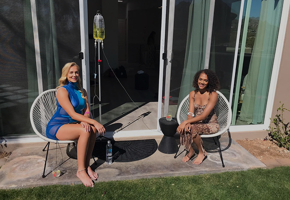 Two women are sitting in chairs in front of a sliding glass door.