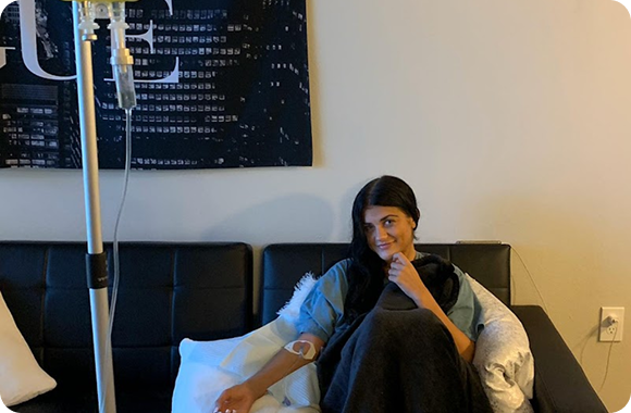 A man and a woman are sitting on a bed with pillows.