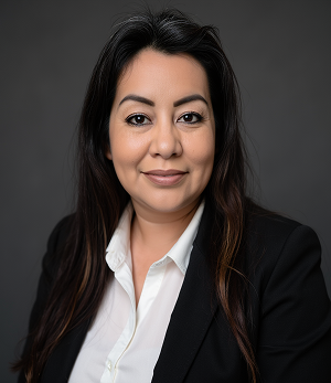 A woman in a black jacket and white shirt is smiling for the camera.
