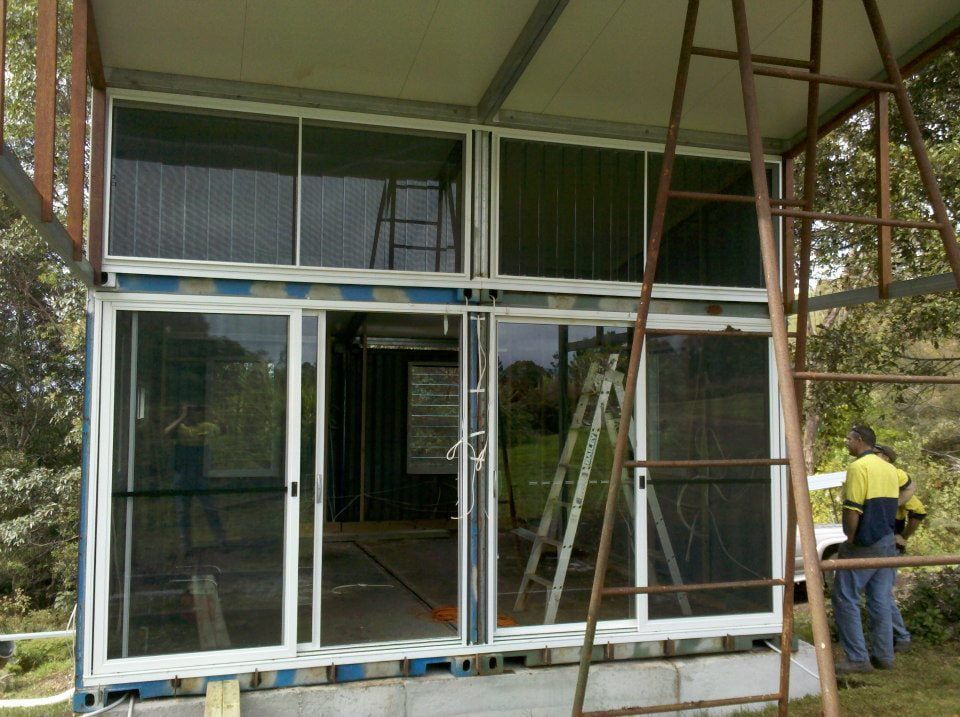A Man Standing on a Ladder in Front of a Building — North Coast Steel Fabrication in South Lismore, NSW