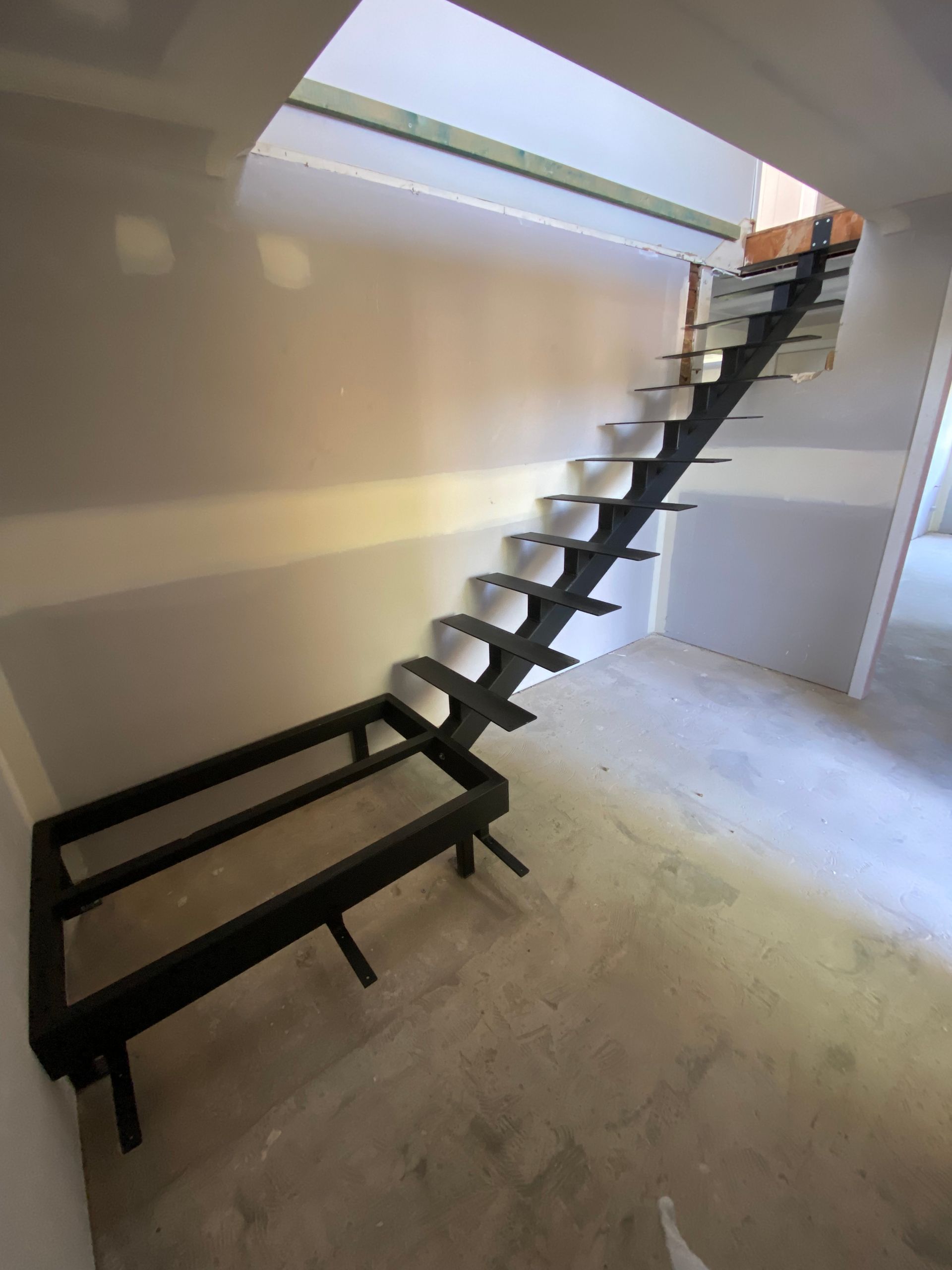 Black metal staircase construction in a new building, steps cantilevered from central stringer.
