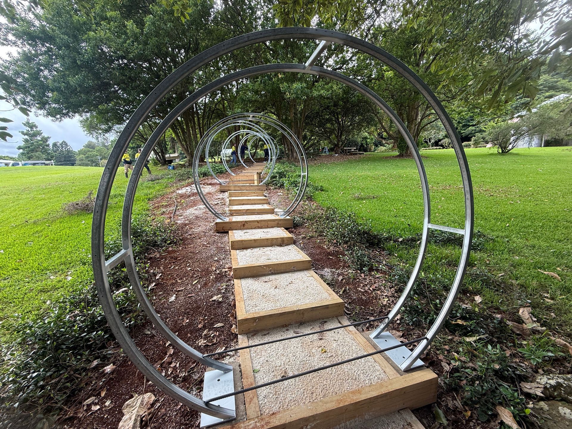 Stone steps and circular metal arches leading through a grassy yard.