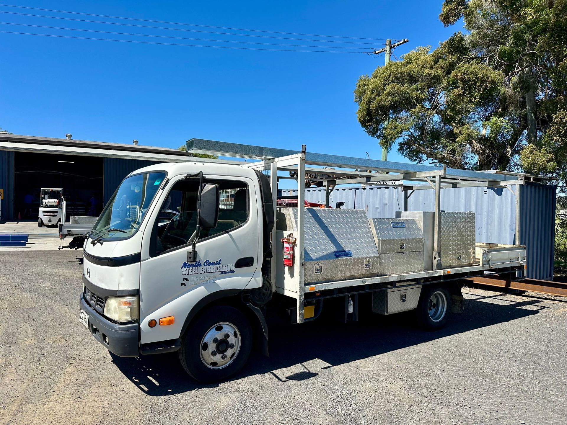 White work truck parked outdoors with toolboxes and storage, sunny day.