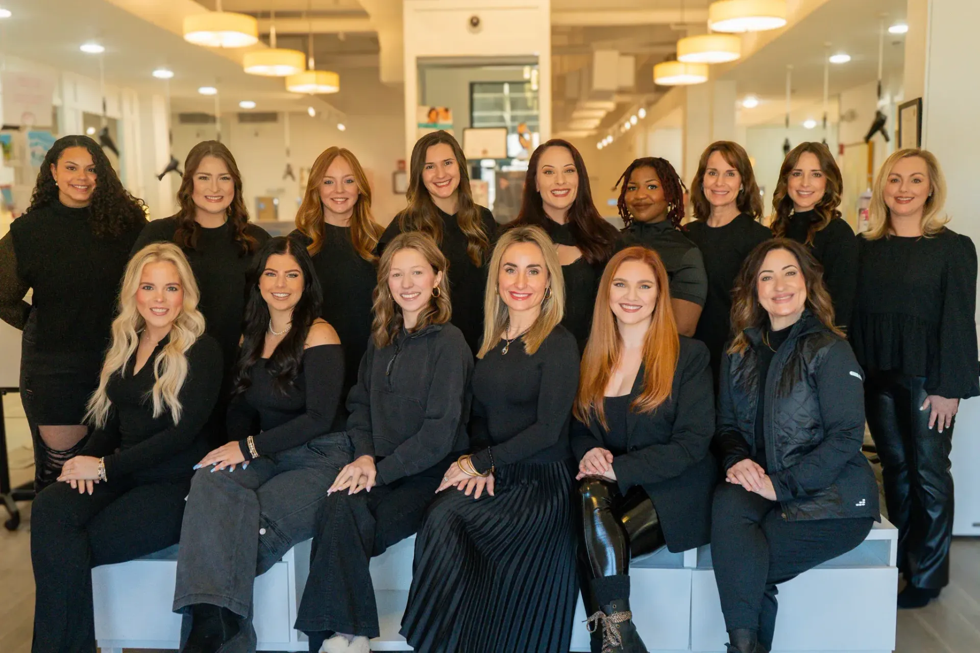 Group of women in black clothing, posing indoors.