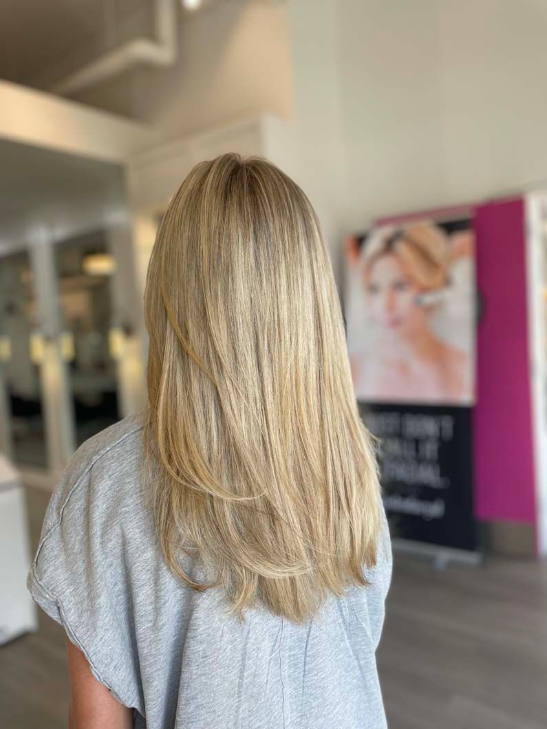 Blonde hair styled with layers, from the back, in a salon.