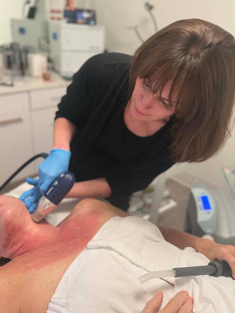Woman administering skincare treatment on another person's neck. Red skin visible.