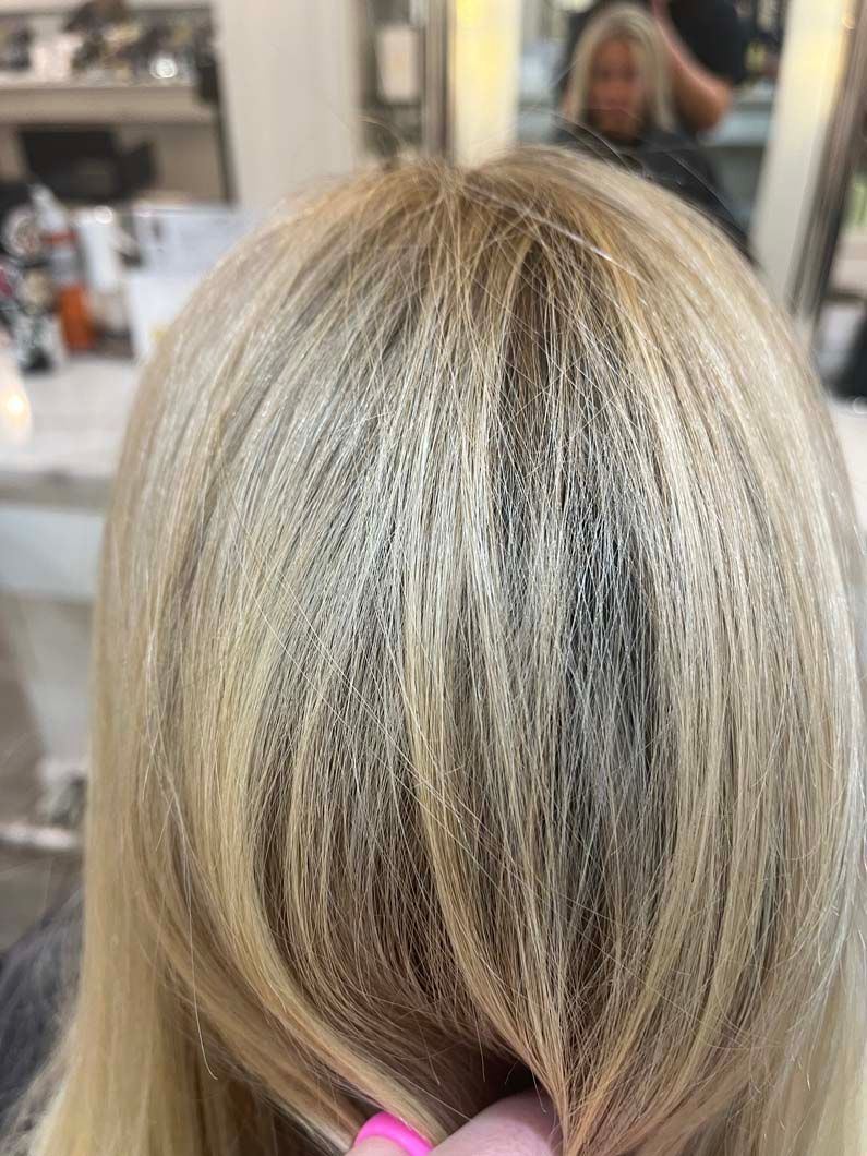 Blonde hair with highlights; streaks of darker hair at the roots.