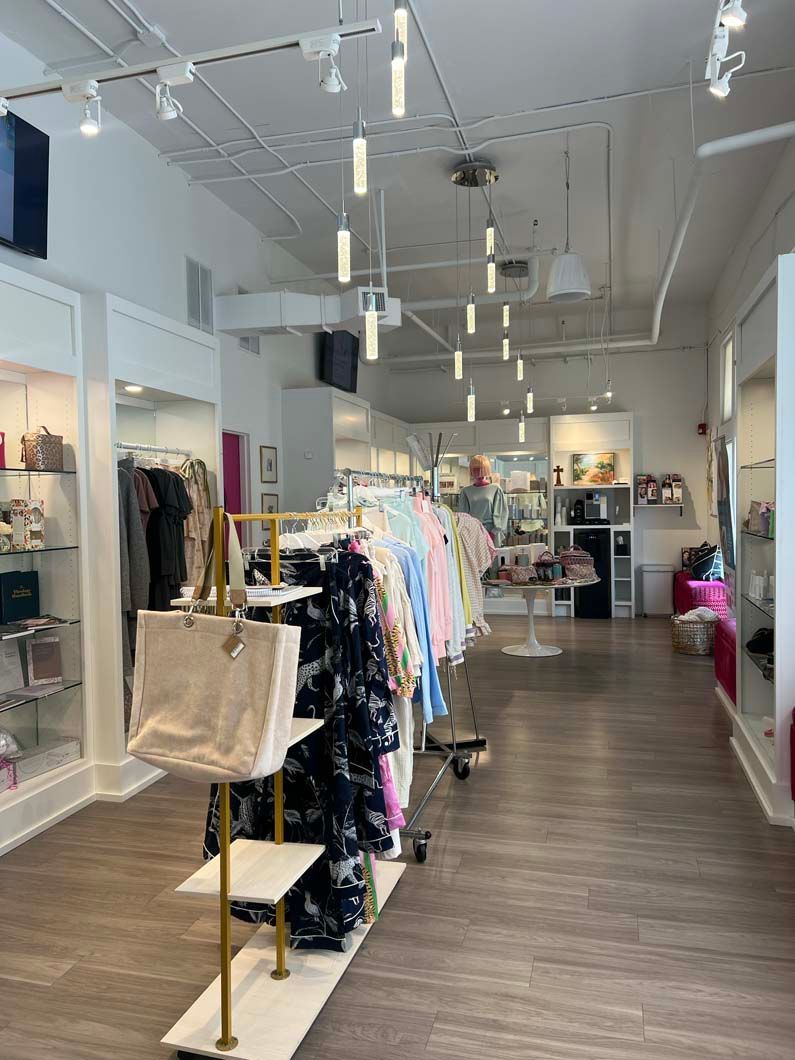 Clothing store interior with racks of clothes, display shelves, and hanging lights.