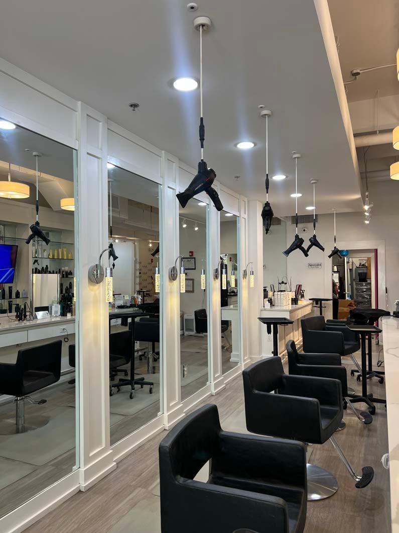 Hair salon interior with mirrors, chairs, and hanging hair dryers.