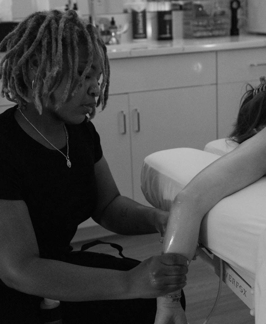 Massage therapist massaging a person's arm on a massage table. Inside a well-lit spa setting.