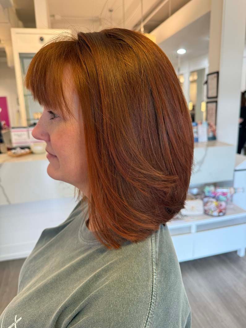 Woman with red, crimped bob hairstyle, side profile view in a salon.