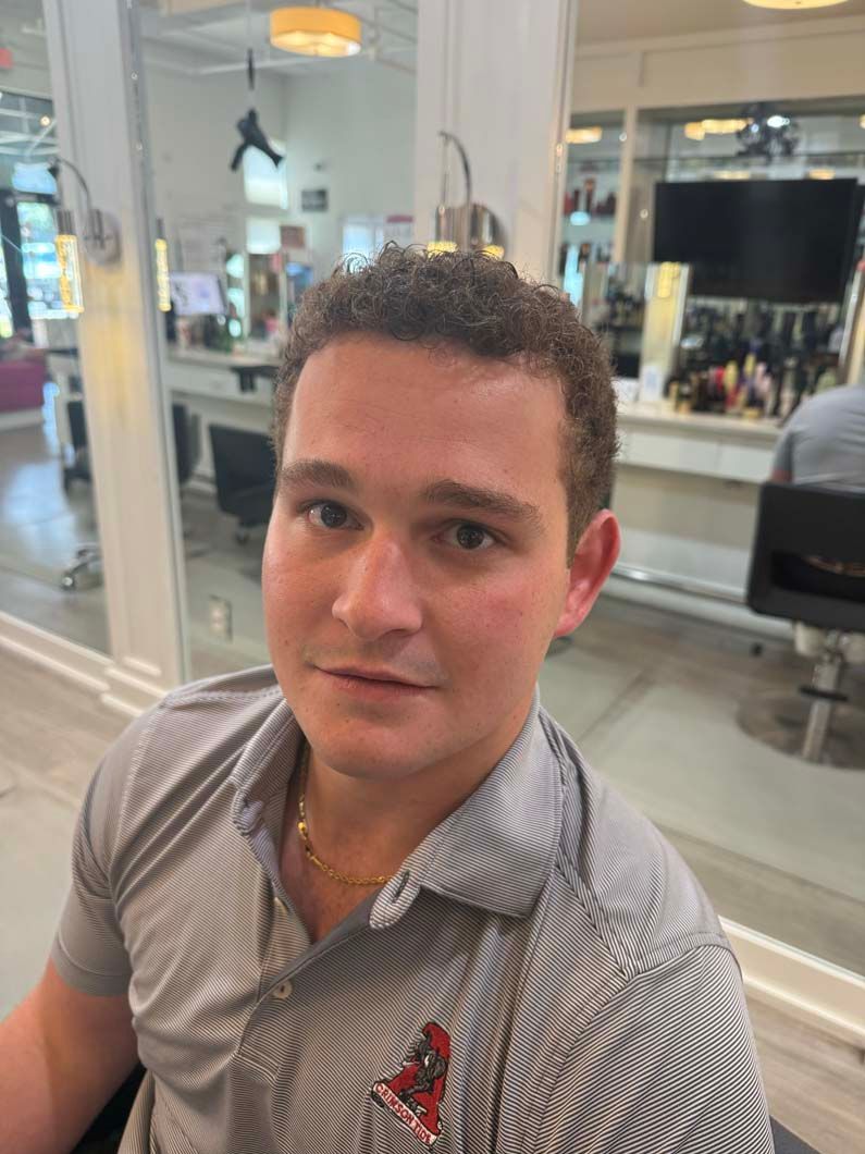 Man in a striped shirt in a salon, looking at the camera.