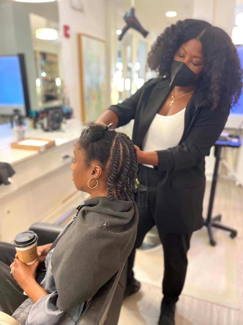 Woman getting her hair styled at a salon. Stylist wearing a mask and a black outfit.