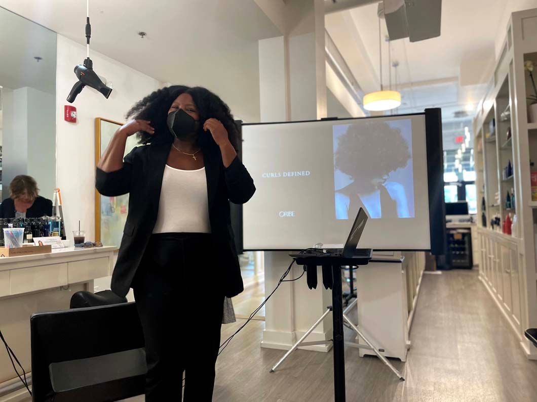 Woman presenting with a projection screen; in a room with a laptop on a tripod.