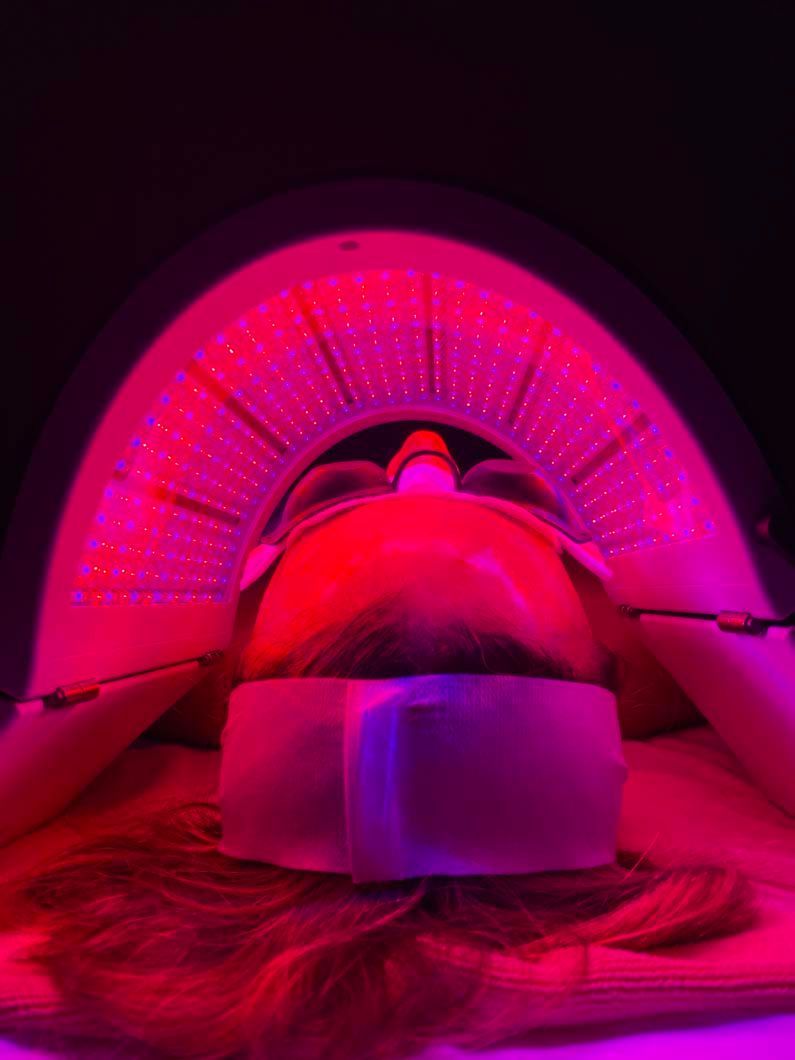 Person undergoing red light therapy facial treatment.
