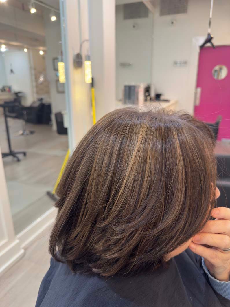 Brown hair with blonde highlights at a salon, pink door in background.