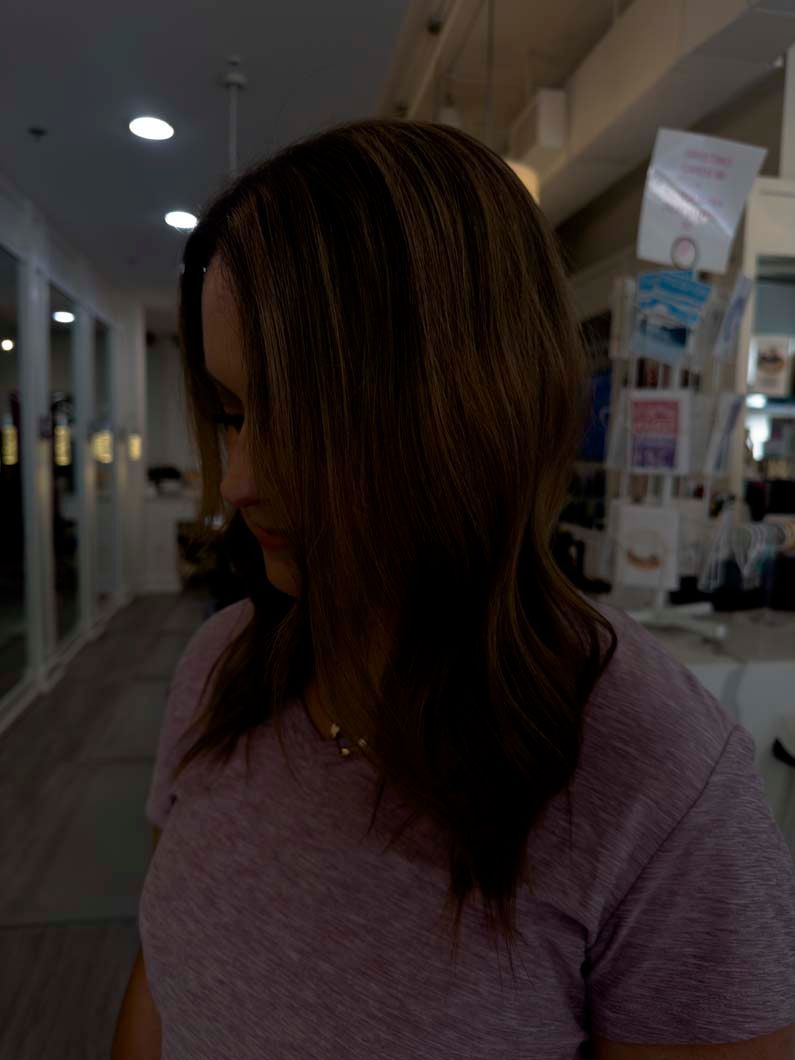 Woman with crimped hair in a salon. Wearing a pink shirt.