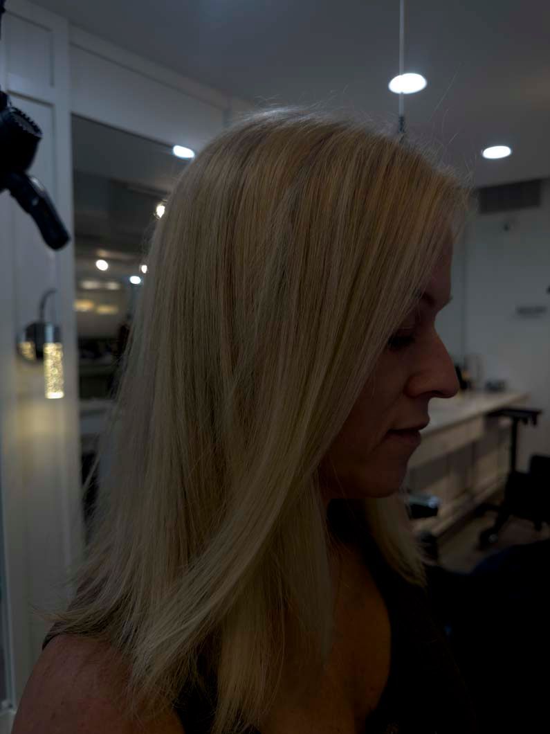 Blonde-haired person with crimped hair, side view, indoors.