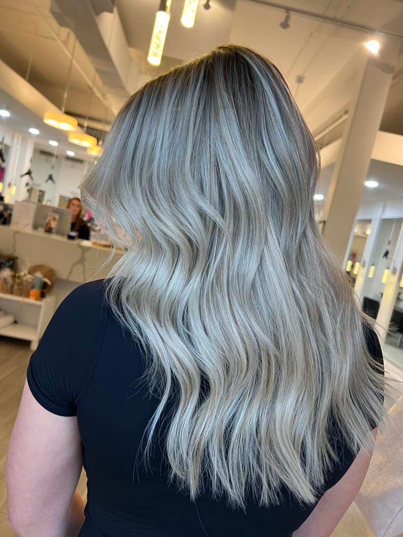 Woman with long, wavy, crimped light blonde hair; wearing a black top.