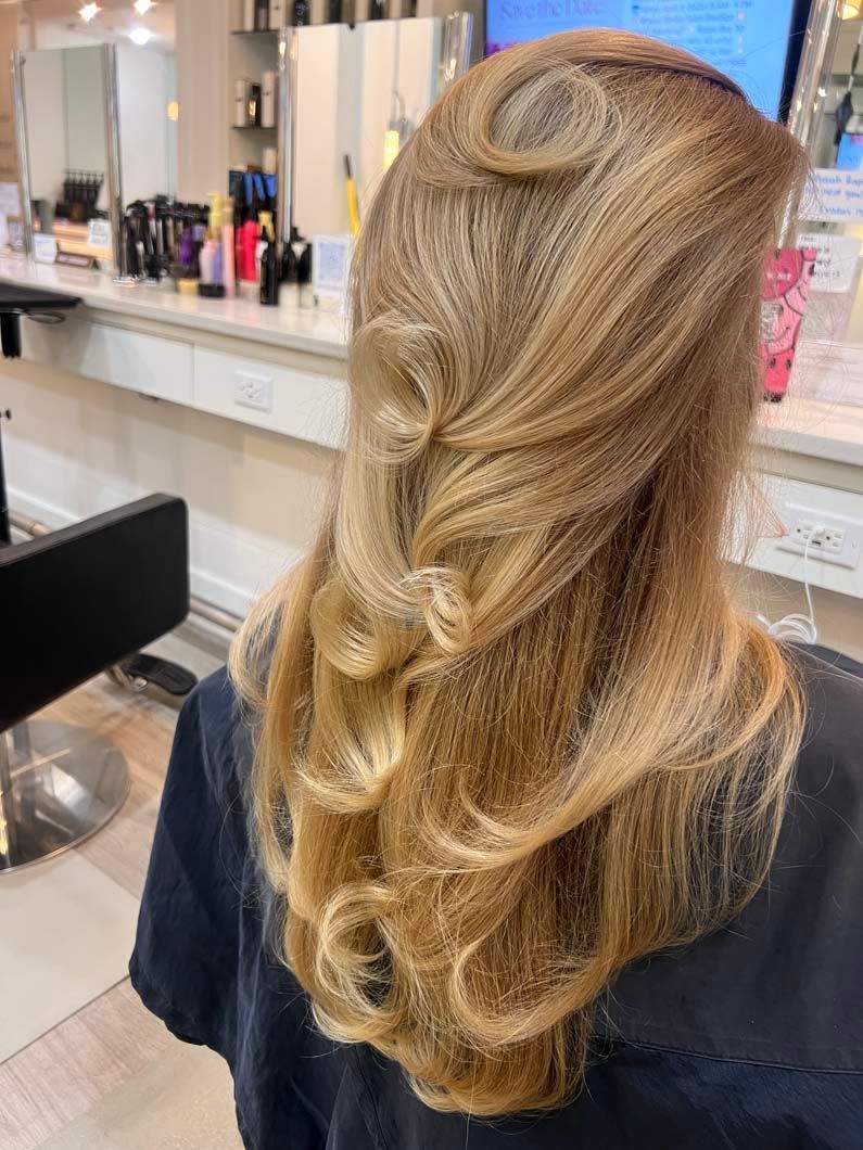 Blonde hair styled in waves and curls in a salon setting.