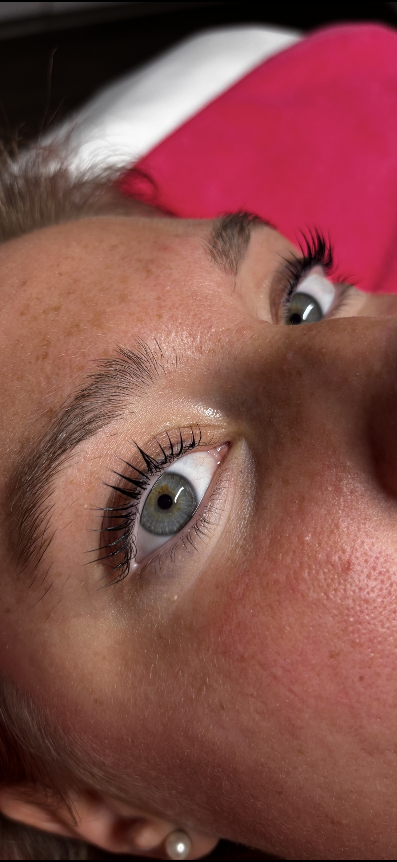 Close-up of a person's face; blue eyes, dark mascara, dark eyebrows, and visible skin pores.