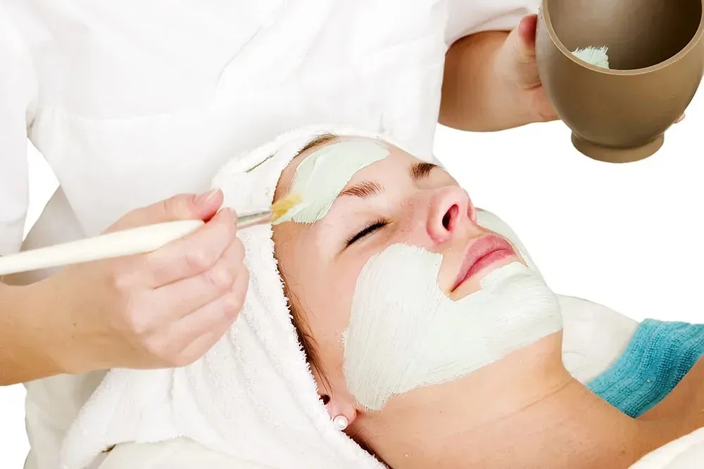 Woman receiving facial mask application at a spa.